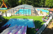 Luftfoto af swimmingpool, vandrutsjebaner og oppustelig giraf på Camping lac Aux Oiseaux i Occitanie, Frankrig.