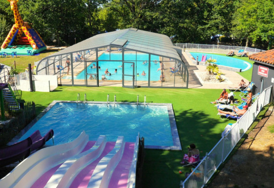 Luftfoto af swimmingpool, vandrutsjebaner og oppustelig giraf på Camping lac Aux Oiseaux i Occitanie, Frankrig.