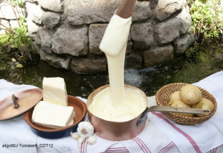 Fransk aligot serveret udenfor med kartofler, smør, hvidløg og en kobbergryde på en dug.