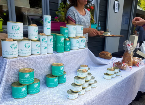Escena de mercado en Camping lac Aux Oiseaux, Occitania, Francia, con latas de comida y degustaciones.