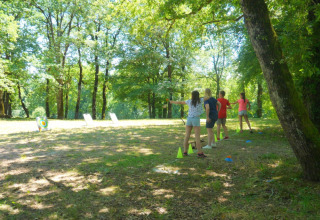 Børn leger bueskydning i skoven på Camping lac Aux Oiseaux, en feriepark i Occitanie, Frankrig.