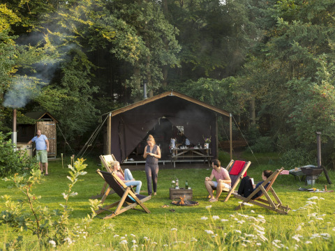 Gruppo rilassato davanti a una tenda a Feather Down Het Wesselink a Salland, parco vacanze in Overijssel.