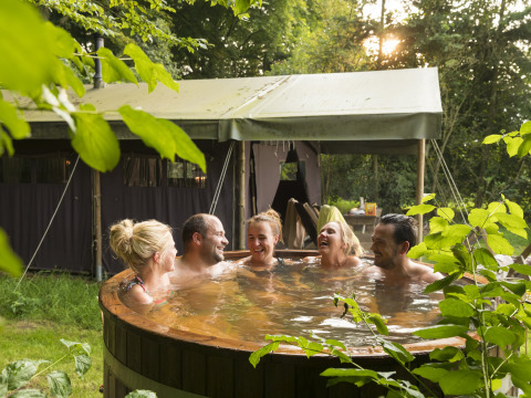 Cinco amigos se relajan en un jacuzzi al aire libre delante de una tienda de campaña en Feather Down Het Wesselink en Salland.