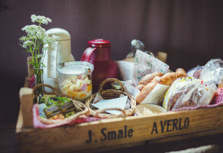 Cestino per la colazione rustico con pane, succo, frutta fresca, fiori e thermos a Het Wesselink in Salland.