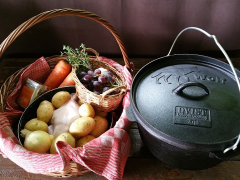 Cesto con patate, carote, cipolle, erbe aromatiche, uva e pentola in ghisa a Het Wesselink, Salland, Paesi Bassi.
