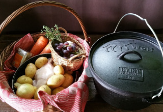 Panier avec pommes de terre, carottes, oignons, herbes, raisins et cocotte en fonte à Het Wesselink, Salland.