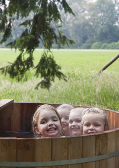Quatre enfants souriants dans un bain chaud en bois au Feather Down Het Wesselink à Salland, Overijssel, Pays-Bas.