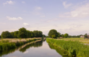 Tranquil canal scene at Feather Down Het Wesselink in Salland, Overijssel, Netherlands, with farmhouses nearby.