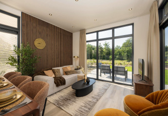 Soggiorno moderno di una lodge con ampie finestre, arredi eleganti, tavolo da pranzo e vista sul giardino.