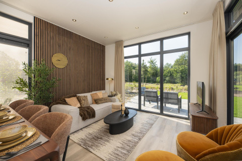 Modernes Lodge-Wohnzimmer mit großen Fenstern, eleganter Einrichtung, Essbereich und Gartenblick.