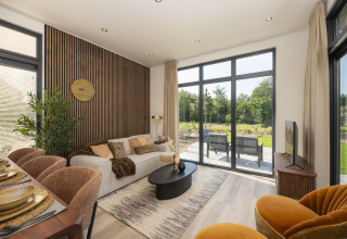 Modernes Lodge-Wohnzimmer mit großen Fenstern, eleganter Einrichtung, Essbereich und Gartenblick.