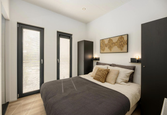 Helles Schlafzimmer in einer Lodge mit Doppelbett, modernen Möbeln, Kunst an der Wand und viel Licht.
