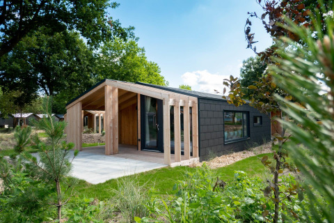 Casa de madera moderna en Panorama Cottage, Kaatsheuvel, Países Bajos, rodeada de vegetación y jardín.