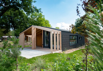 Moderne houten lodge bij Panorama Cottage, Kaatsheuvel, Nederland, omgeven door natuur en tuin.