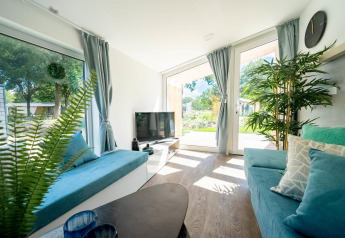Lys og moderne stue i Panorama Cottage i Kaatsheuvel, Holland, med store vinduer og elegante blå sofaer.