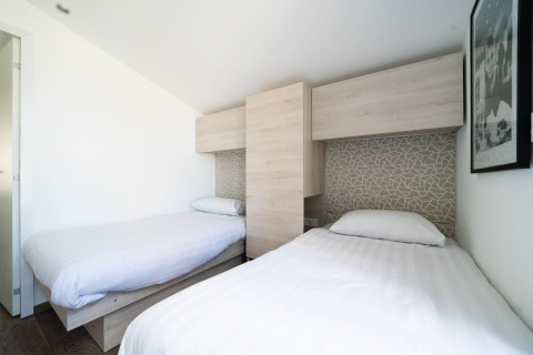 Zwei Einzelbetten in einem hellen Zimmer im Panorama Cottage in Kaatsheuvel, Niederlande, modern eingerichtet.