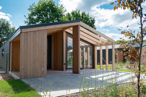 Panorama Cottage Lodge in Kaatsheuvel, Niederlande, mit moderner Holzstruktur und Glasfront bei Sonnenschein.