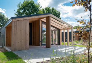 Lodge Panorama Cottage en Kaatsheuvel, Países Bajos, con diseño de madera moderna y fachada de vidrio al sol.