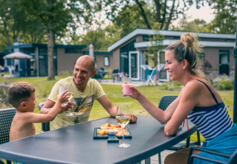 Familie nyder udendørs drinks og snacks ved Panorama Cottage lodge i Kaatsheuvel, Holland.