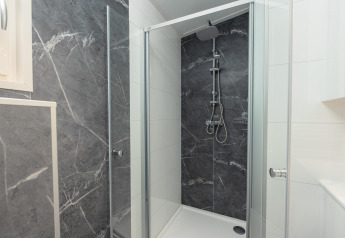 Moderne Dusche mit grauen Marmorwänden und Glastür im Loevestein Deluxe im Veluwepark de Bosgraaf.