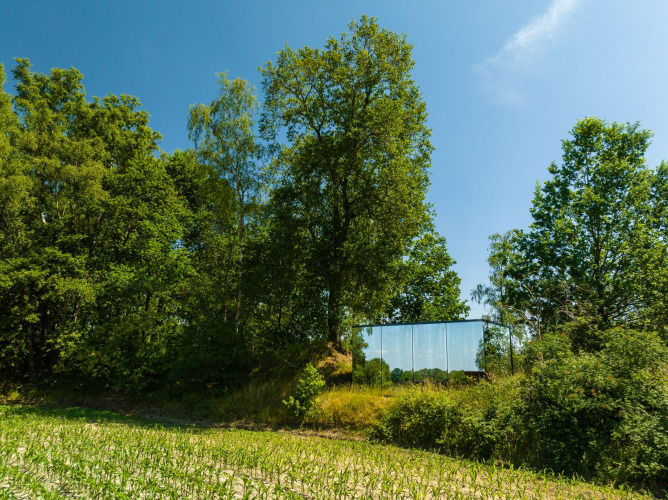 Mirrored tiny house, ÖÖD Suite, discreetly nestled among lush green trees at Wilsumer Berge, Germany.