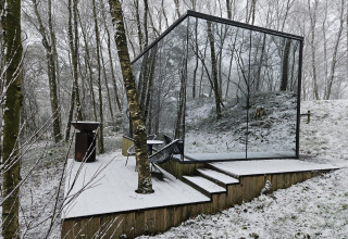 De ÖÖD Suite tiny house met spiegelwanden staat in een besneeuwd bos bij Wilsumer Berge, Duitsland.