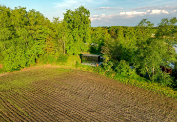 Aerial view of ÖÖD Suite tiny house at Wilsumer Berge, Germany, nestled by fields and green forest trees.