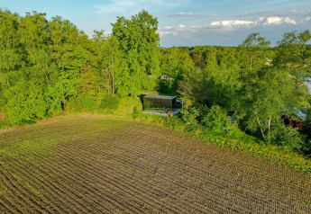 Vue aérienne de la tiny house ÖÖD Suite à Wilsumer Berge, Allemagne, entourée de champs et d’arbres.