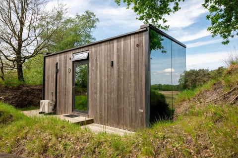Tiny house ÖÖD Suite op Wilsumer Berge in Duitsland, met houten gevel en spiegelend glazen wand.