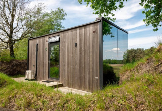 Tiny house ÖÖD Suite op Wilsumer Berge in Duitsland, met houten gevel en spiegelend glazen wand.