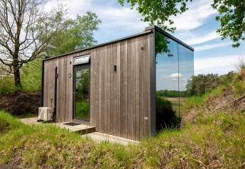 Tiny house ÖÖD Suite op Wilsumer Berge in Duitsland, met houten gevel en spiegelend glazen wand.