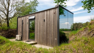 Casa tiny llamada ÖÖD Suite en Wilsumer Berge, Alemania, con fachada de madera y pared de vidrio reflectante.