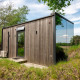 Casa tiny llamada ÖÖD Suite en Wilsumer Berge, Alemania, con fachada de madera y pared de vidrio reflectante.