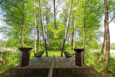 Facciata a specchio dell’ÖÖD Suite a Wilsumer Berge, Germania, riflettendo la foresta verde circostante.