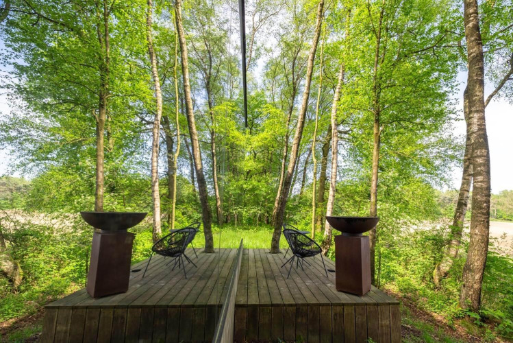 Mirror facade of ÖÖD Suite at Wilsumer Berge in Germany reflecting the lush green forest surroundings.