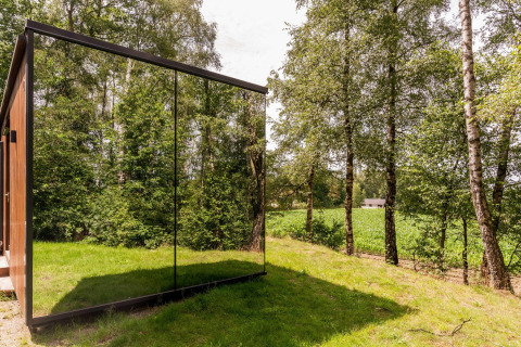 Spektakulær udsigt over det grønne landskab og spejlglasfacaden på ÖÖD Suite tiny house i Wilsumer Berge, Tyskland.