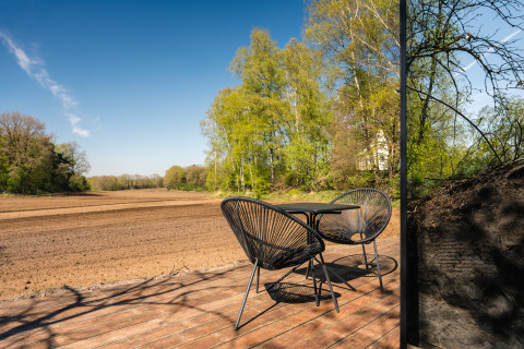 Buitenterras bij ÖÖD Suite Wilsumer Berge, Duitsland, met twee stoelen, tafel en uitzicht op veld en bos.