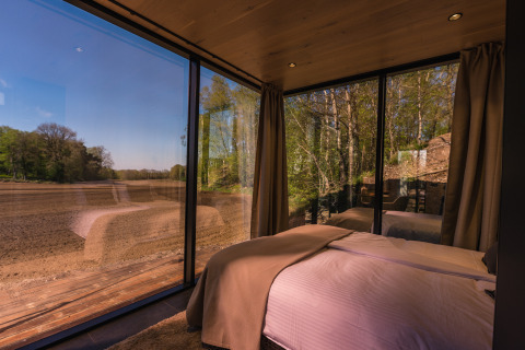 Uitzicht vanuit een slaapkamer in het ÖÖD Suite tiny house bij Wilsumer Berge met grote glazen ramen.