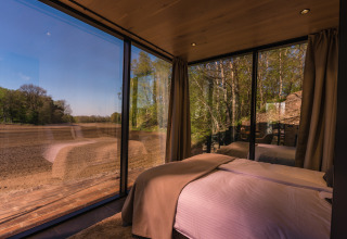 Uitzicht vanuit de slaapkamer van het ÖÖD Suite tiny house in Wilsumer Berge met glazen wanden.