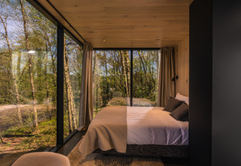 Slaapkamer in het ÖÖD Suite tiny house bij Wilsumer Berge in Duitsland, met panoramisch boszicht.