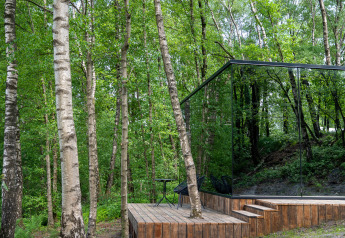 Spejlet tiny house ÖÖD Suite ved Wilsumer Berge i Tyskland, omgivet af grøn frodig skov og birketræer.