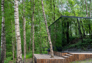 Das verspiegelte Tiny House ÖÖD Suite in Wilsumer Berge, Deutschland, umgeben von grünen Birkenwäldern.