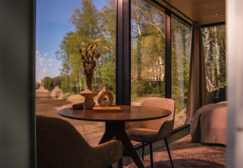 Vista interior de la ÖÖD Suite en Wilsumer Berge, Alemania, con ventanas panorámicas y vista al bosque.