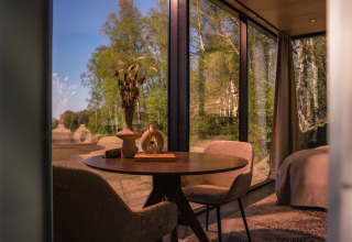 Innenansicht der ÖÖD Suite in Wilsumer Berge, Deutschland, mit Panoramafenstern und Waldblick.