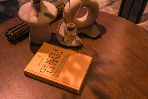 Table chaleureuse à la tiny house ÖÖD Suite avec le livre 'Gentle Living' et un diffuseur à Wilsumer Berge, Allemagne.