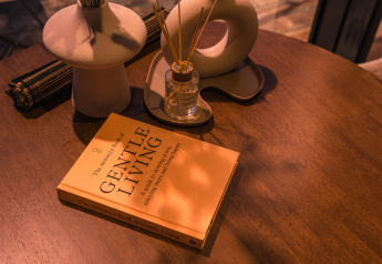 Table chaleureuse à la tiny house ÖÖD Suite avec le livre 'Gentle Living' et un diffuseur à Wilsumer Berge, Allemagne.