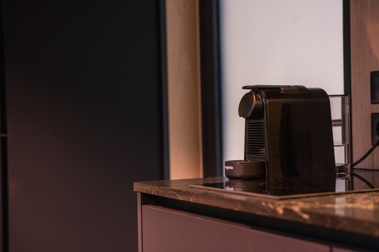 A black coffee machine sits on a marble countertop in the ÖÖD Suite tiny house at Wilsumer Berge, Germany.