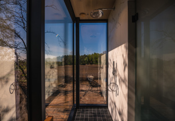 Douche met glazen wanden in ÖÖD Suite op Wilsumer Berge, Duitsland, met uitzicht op terras en natuur.