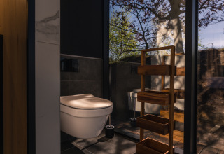 Baño moderno en la casa diminuta ÖÖD Suite en Wilsumer Berge, Alemania, con pared de cristal y vista natural.