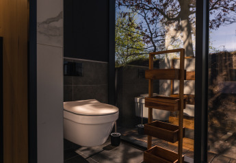 Salle de bain moderne dans la tiny house ÖÖD Suite, Wilsumer Berge, Allemagne, avec paroi vitrée et vue nature.